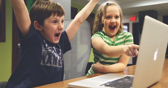 Niños celebrando delante de un ordenador